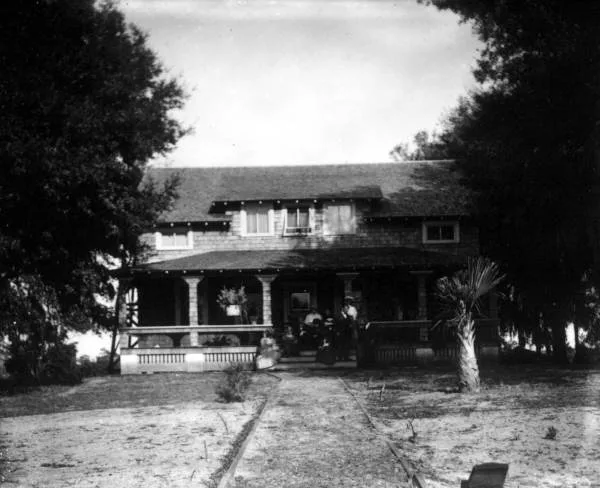 Historic photo of a Florida family sitting on the deep front porch of their home, around 1900