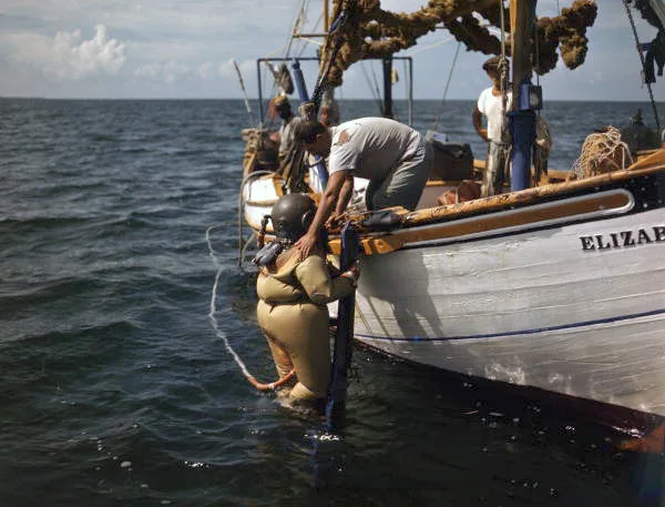 Historic color photo of a Greek sponge diver in a brass helmet on a boat at Tarpon Springs