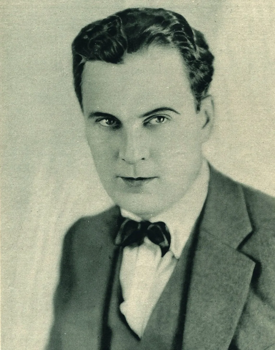 Studio portrait of a well-dressed man from the early 1920s, hair combed back.