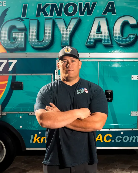 Chad, owner of I Know A Guy AC, standing in front of the branded turquoise truck